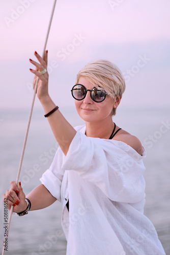 Beautiful blonde happy woman enjoying sunset on the yacht in the sea. Travel, adventure, relaxation concept  © k8most