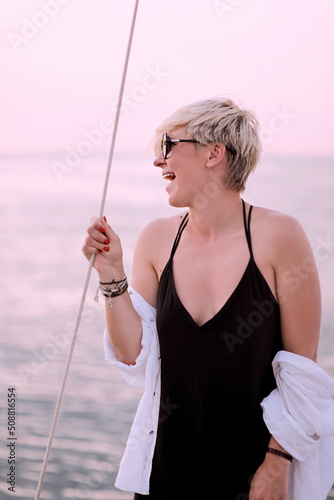 Beautiful blonde happy woman enjoying sunset on the yacht in the sea. Travel, adventure, relaxation concept 