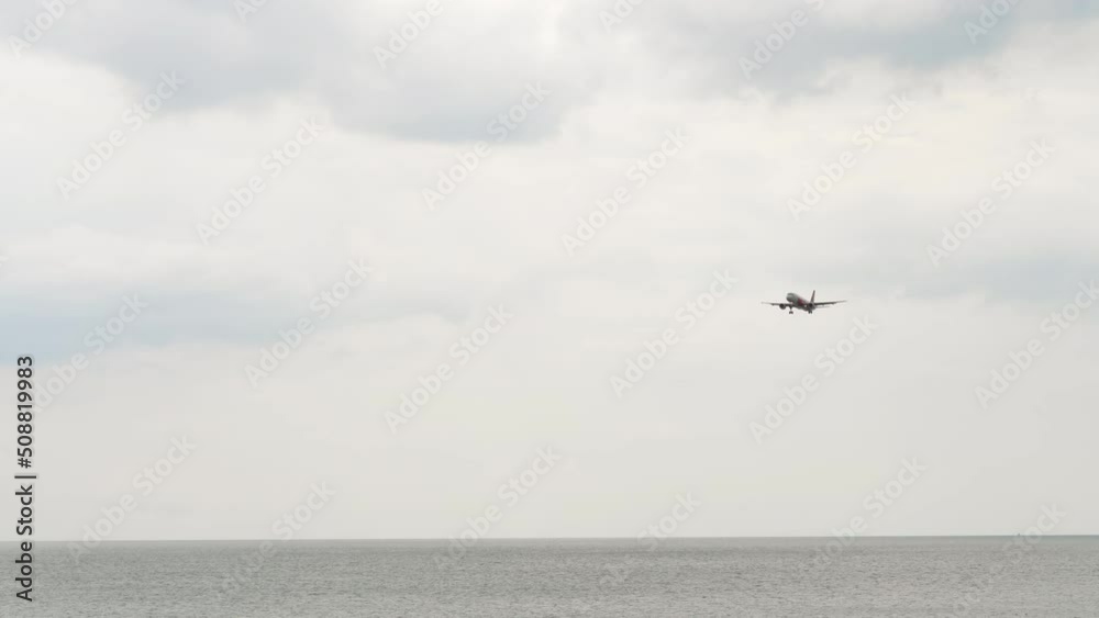 Long shot of airplane approaching to land at Phuket airport. Airplane flies over the ocean. Tourism and travel concept Long shot of airplane approaching to land at Phuket airport. Airplane flies over the ocean. Tourism and travel concept