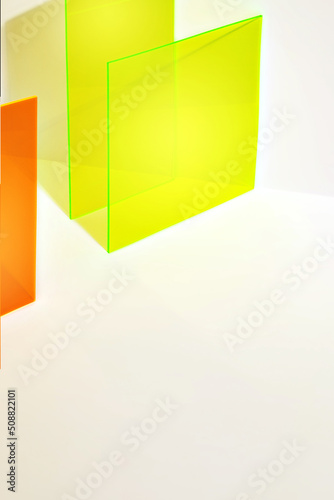 Saturated orange and neon yellow acrylic sheet with long shadow on a bright lit white background. Stylish abstract background. Colourful stage for advertising, promoting new products or packaging.