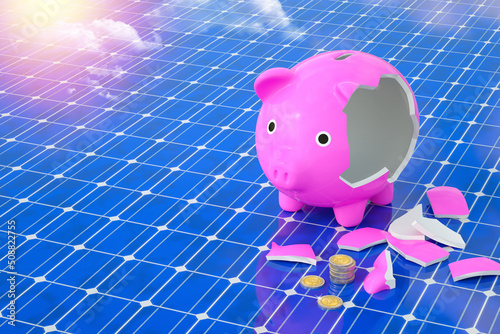 Broken piggy bank on solar panel in bright blue sky for not cost-effective concept in energy industrial. 