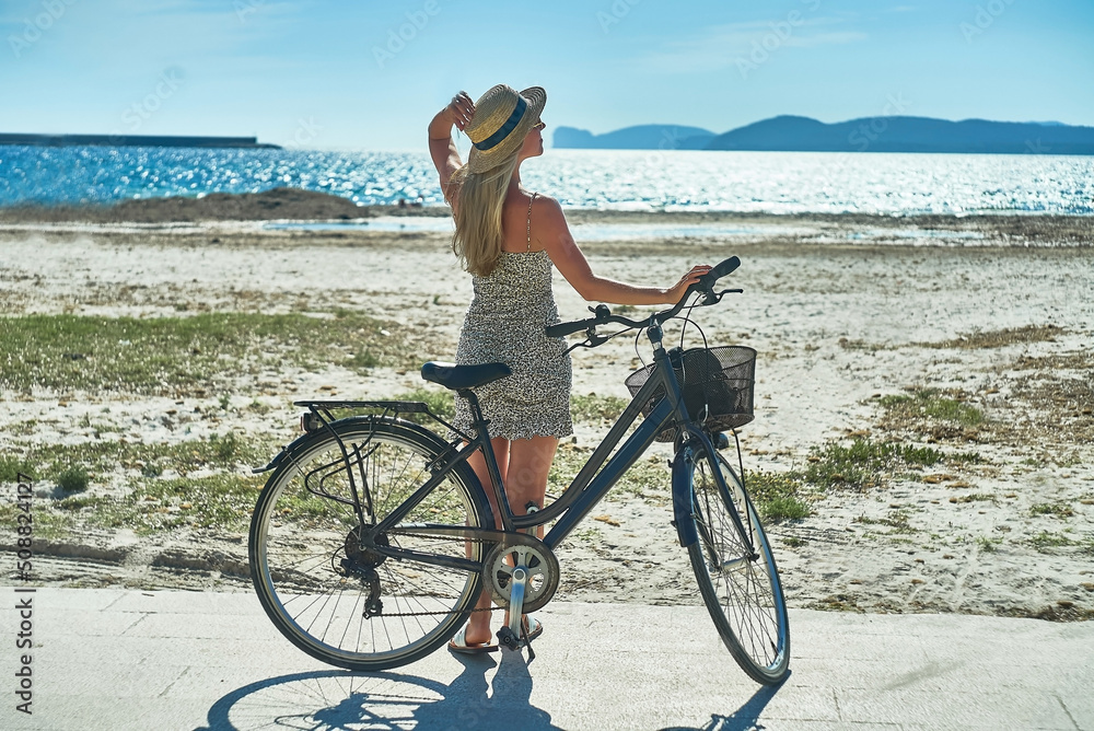 Carefree woman with bike riding on sand beach having fun, on the seaside promenade on a summer day. Carefree woman with bike riding on sand beach having fun, on the seaside promenade on a summer day.