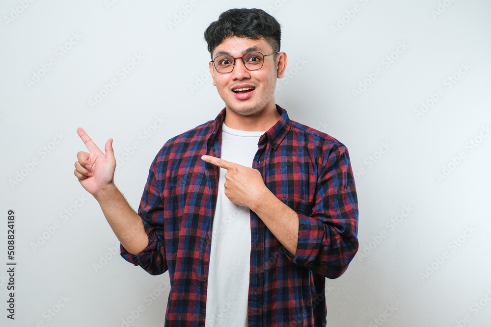 Young handsome asian man pointing with hand finger to the side looking at the camera. Young handsome asian man pointing with hand finger to the side looking at the camera.