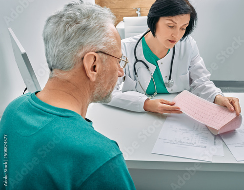 Diagnostic heart diseases, heart attacks, and tachycardia in elderly people. Doctor consulting senior man on results of his cardiogram and test