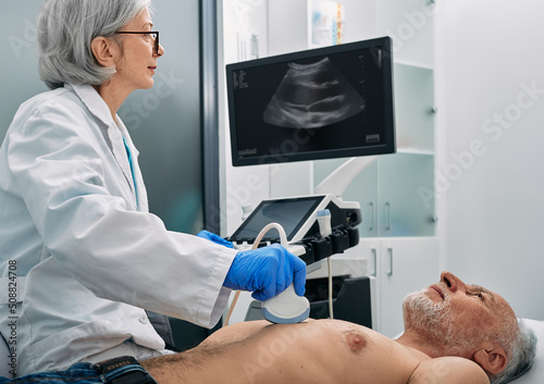 Heart ultrasound exam for senior man with ultrasound specialist while medical exam. Heart health exam with ultrasound scan machine photo