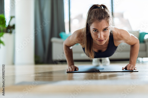 Young woman exercising push-ups and looking at camera