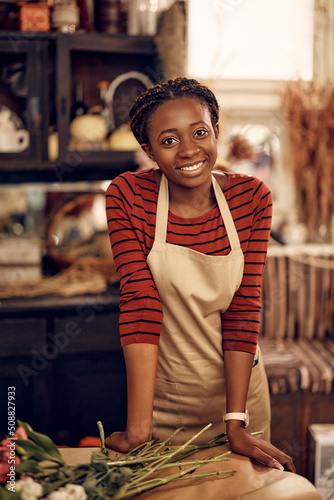 Portrait of happy black female florist at flower shop looking at camera.