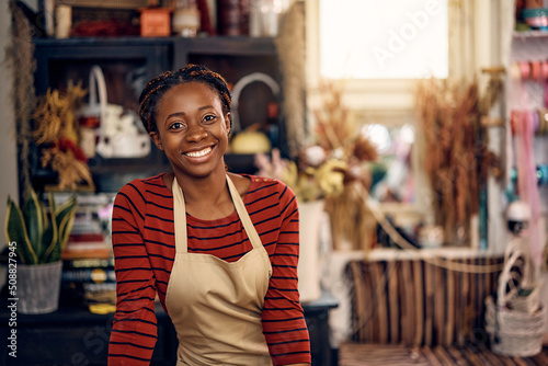Happy African American woman working as florist at flower shop and looking at camera.
