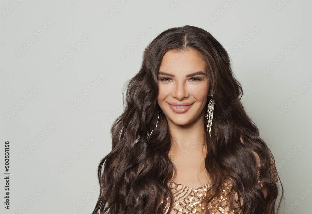 Happy smiling brunette woman with makeup and long wavy hairstyle on white background