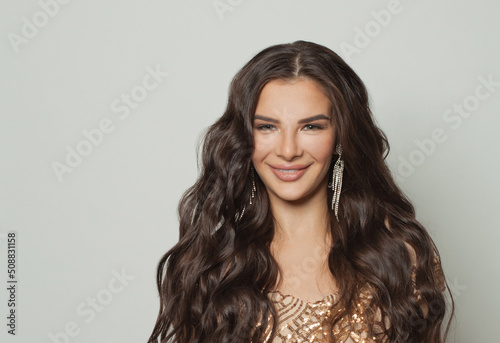 Happy smiling brunette woman with makeup and long wavy hairstyle on white background