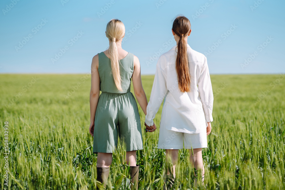 Two Beautiful woman in the green field. Nature, vacation, relax and lifestyle. Summer landscape. Fashion, style concept. Two Beautiful woman in the green field. Nature, vacation, relax and lifestyle. Summer landscape. Fashion, style concept.