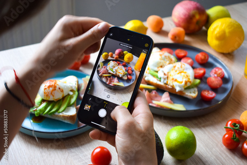 Taking a photo of a poached benedict egg on an avocado toast for a social media post.