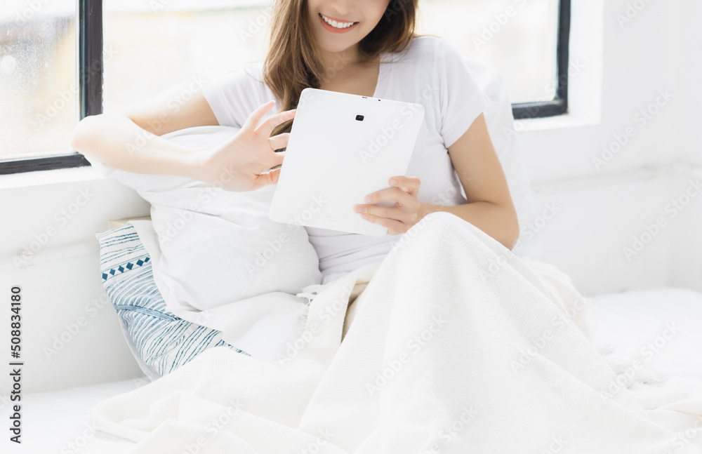 Unrecognizable happy young woman use tablet computer and scrolling through tablet on bed at bedroom with happiness Pretty girl using tablet for social media shopping online study and watching movie Unrecognizable happy young woman use tablet computer and scrolling through tablet on bed at bedroom with happiness Pretty girl using tablet for social media shopping online study and watching movie