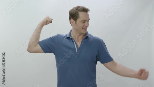 Fun cute strong man raising arms and showing biceps isolated on white background, expressing power ambitions to succeed. Young fit man expressing endurance. Strong athlete concept.