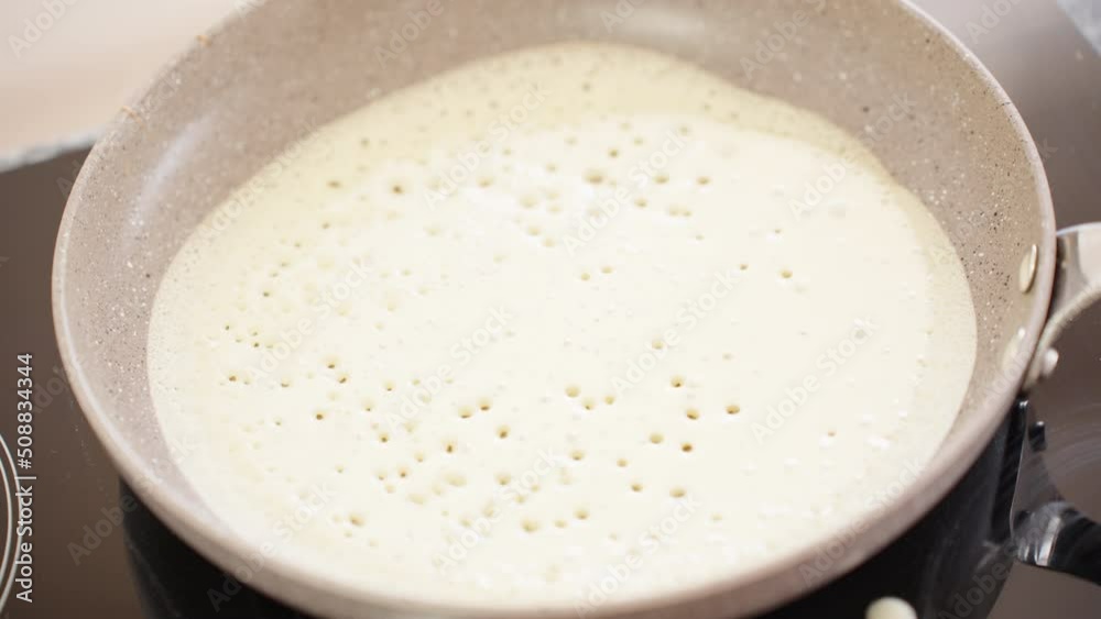 Close-up. The pancake is fried in a frying pan. Bubbles of dough burst. Close-up. The pancake is fried in a frying pan. Bubbles of dough burst.