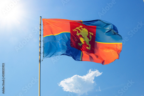 Wind waving the flag of Krasnoyarsk against the background of a blue sky with sun photo
