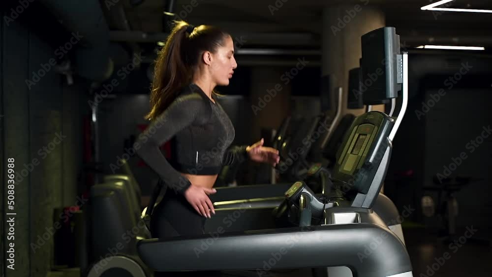 girl athlete runs on a treadmill in the gym. dark background