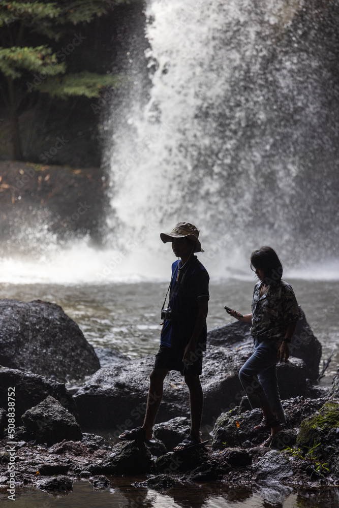 Fototapeta premium People are in the forest watching waterfalls and watching the beautiful nature playing in the water and relaxing on vacation. At Khao Yai National Park, Thailand, 16-05-2022