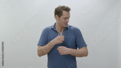 Man who is sweating heavily isolated on white background smells bad.Young man worried and showing sweating spot problem with sweating, sniffing armpit.Bad odor, excessive sweating concept.