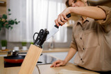 Woman pulling out a kitchen knife from a wooden block