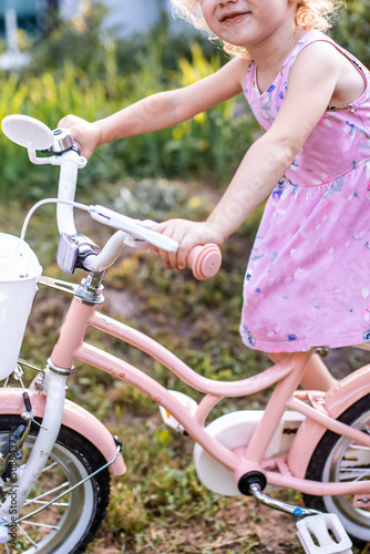 Little girl blonde 3 years old learns to ride two-wheeled bicycle