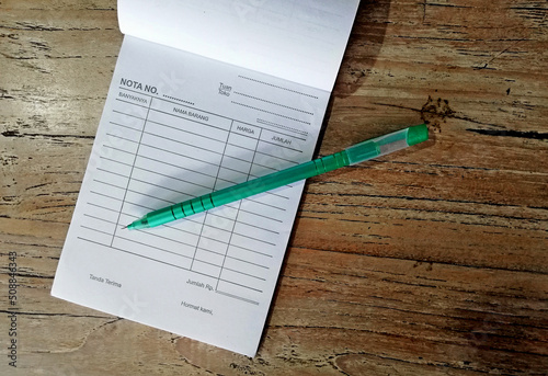 Small notebook and pen,placed on brown wooden table.Bussiness concept