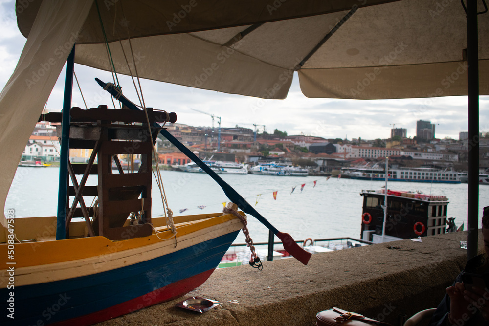 Wooden replica sailboat used to transport port wine with Rio Douro and Porto harbor in background