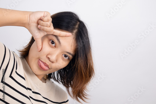 Portrait of an Asian woman showing a loser symbol with a funny tongue sticking out.