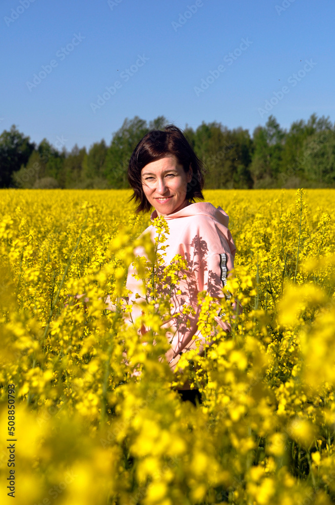 Beautiful young woman in the middle of a field of yellow rapeseed or canola flowers. Beautiful young woman in the middle of a field of yellow rapeseed or canola flowers.