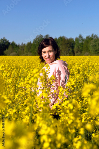 Beautiful young woman in the middle of a field of yellow rapeseed or canola flowers.
