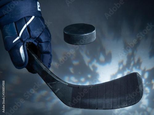 Closeup of a black ice hockey stick shooting a puck against a dreamy background. photo