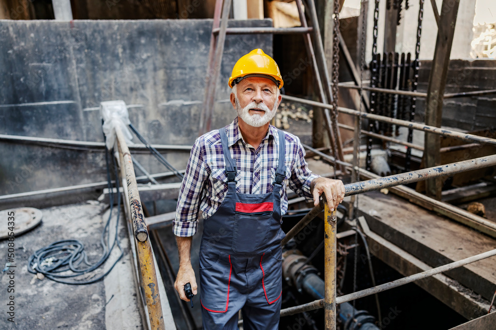 A senior factory worker climbs up the stairs in the facility and checks on metal works. A senior factory worker climbs up the stairs in the facility and checks on metal works.
