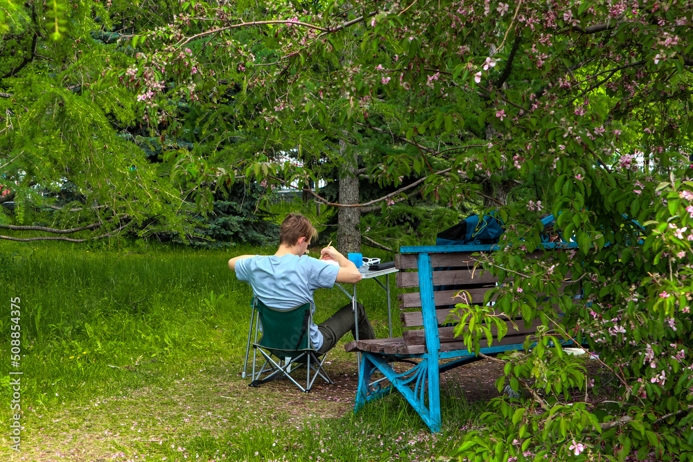 the guy is painted in the open air.rear view. draw in the park. draw a landscape. the guy is painted in the open air.rear view. draw in the park. draw a landscape.
