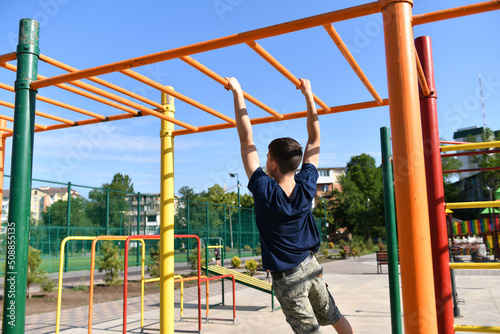 a teenage boy trains on a sports ground outdoors, he does physical exercises, a healthy lifestyle, a bright sunny day in summer