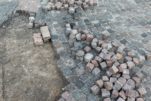 Stone pavement, construction worker laying cobblestone rocks on sand.