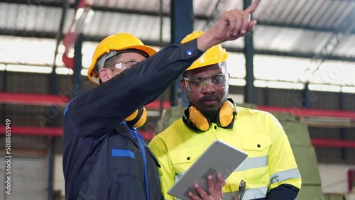 Team multiracial colleague, professional industrial engineer and technician, worker wearing safety uniform, glasses, hard hat, using tablet discuss, analysis, process control in manufacturing factory.