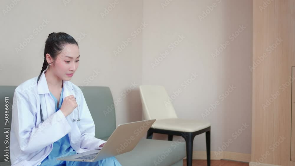 Attractive, Professional female asian doctor in white medical coat. While sitting on sofa, making conference video call on laptop, consulting distance patient online. Telemedicine healthcare concept. Attractive, Professional female asian doctor in white medical coat. While sitting on sofa, making conference video call on laptop, consulting distance patient online. Telemedicine healthcare concept.