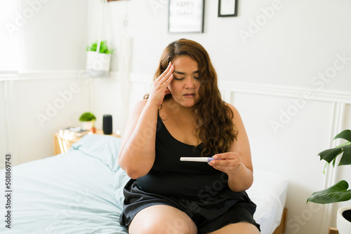 Sad worried woman holding a pregnancy test