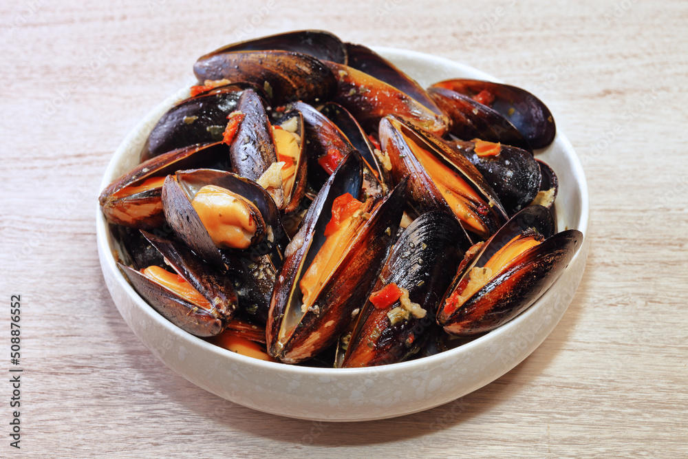 Mussels in garlic cream sauce on wooden table Mussels in garlic cream sauce on wooden table