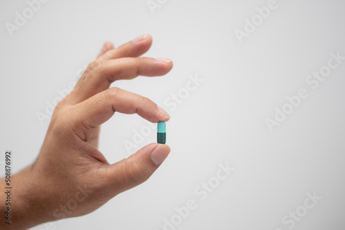 hand holding medicine capsule white background