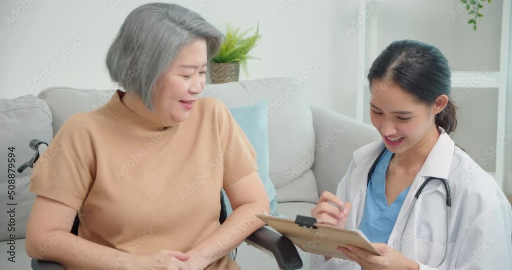 Asian female doctor smiling and filling elderly patient checkup form during visit, writing data to document paper clipboard, medical history, disease prevention, elderly Asian woman checkup. Asian female doctor smiling and filling elderly patient checkup form during visit, writing data to document paper clipboard, medical history, disease prevention, elderly Asian woman checkup.