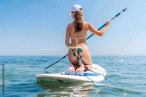 SUP Stand up paddle board. Young woman sailing on beautiful calm sea with crystal clear water. The concept of an summer holidays vacation travel, relax, active and healthy life in harmony with nature.