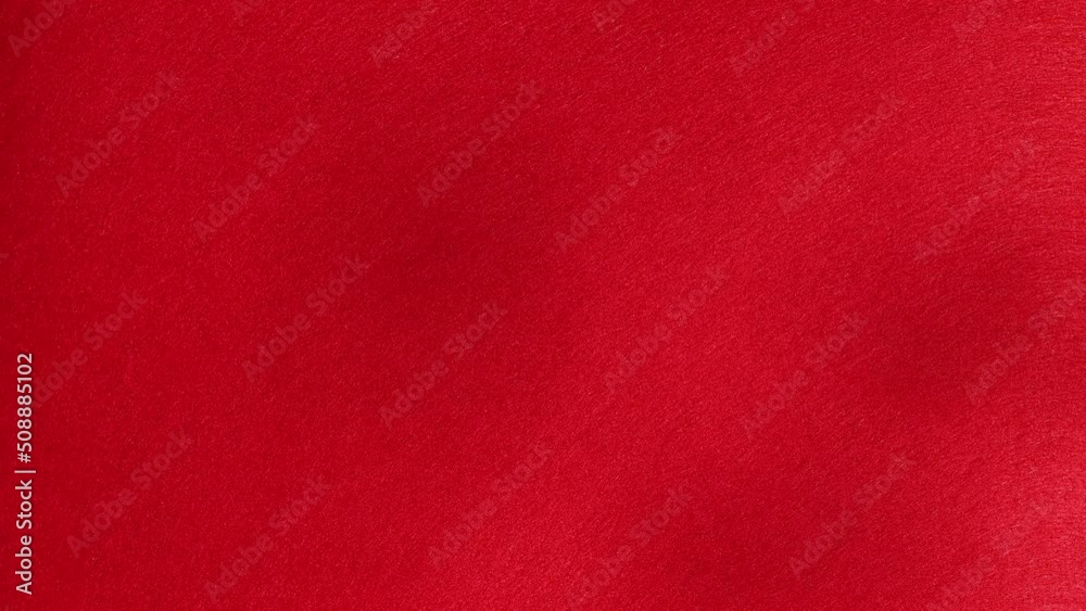 Red background with blurred shadows from plants on a bright sunny day, close-up.