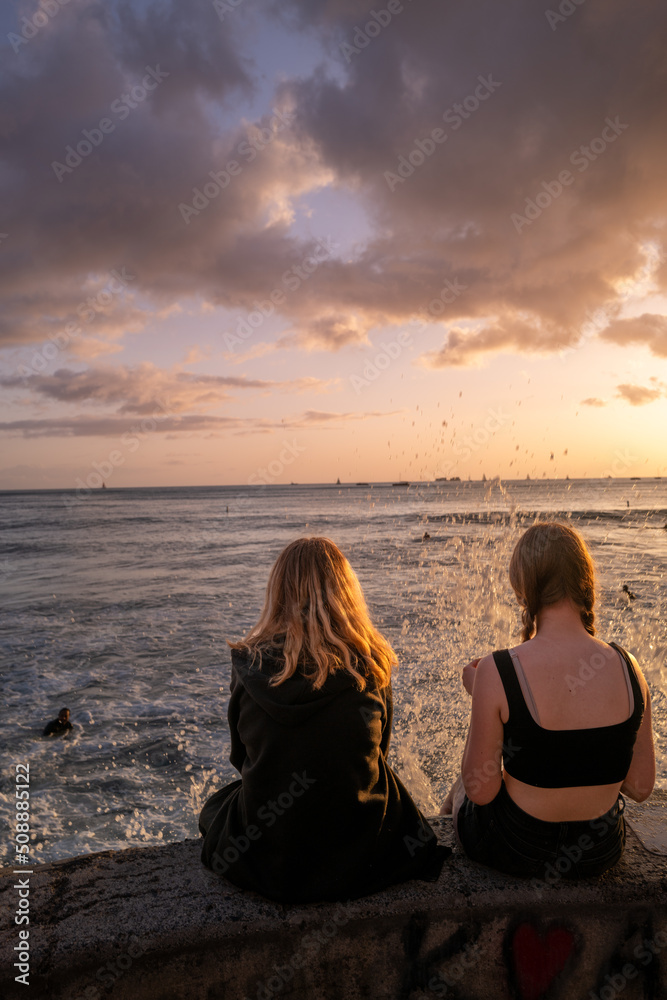 Young Couple Enjoying Sunset Together as a Wave Splashes
