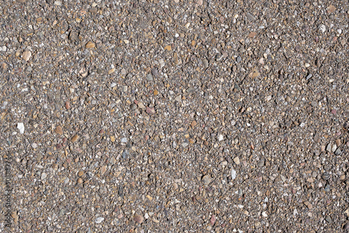 Superficie y textura de asfalto de carretera rural con mucha piedra y guijarro