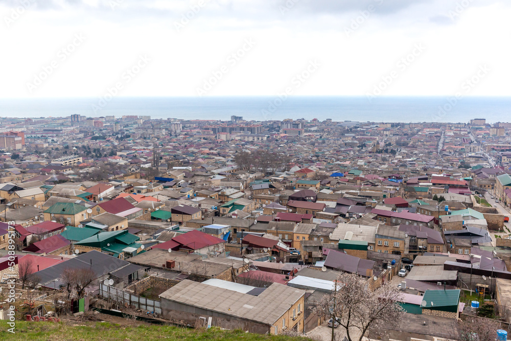Old town along the blue sea, top view. The ancient city of Derbent in Dagestan with streets and houses is located next to the fortress.