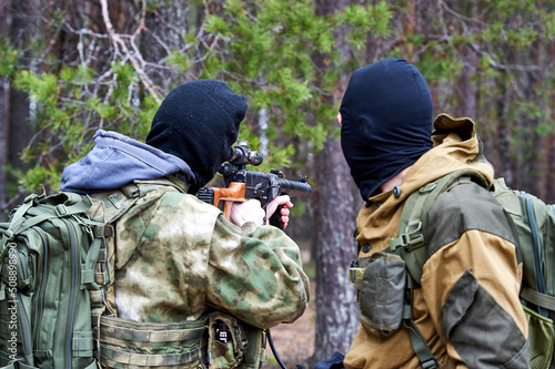 A man in a balaclava with a sniper rifle aiming in the woods photo