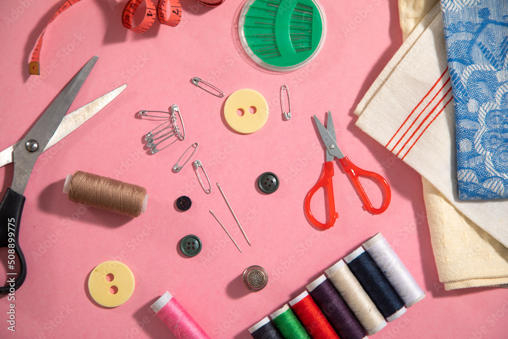 Sewing tools on the pink paper background. Sewing tools on the pink paper background.