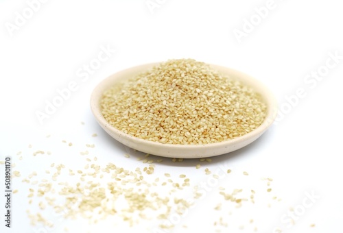 white sesame seeds in a plate on a white background