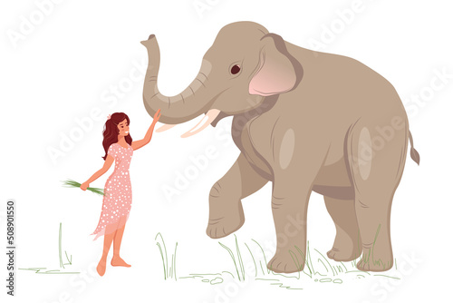 A young woman stands with an elephant, walks and feeds grass to a large elephant © Sg.Lapchi